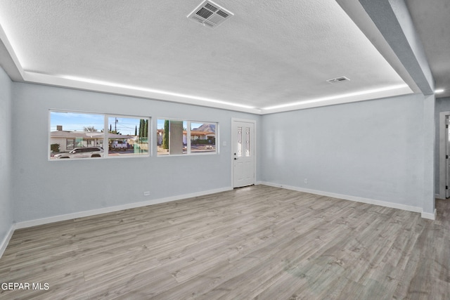 unfurnished room featuring a textured ceiling and light hardwood / wood-style flooring