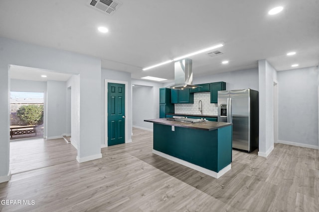 kitchen with backsplash, island exhaust hood, light hardwood / wood-style floors, and stainless steel fridge