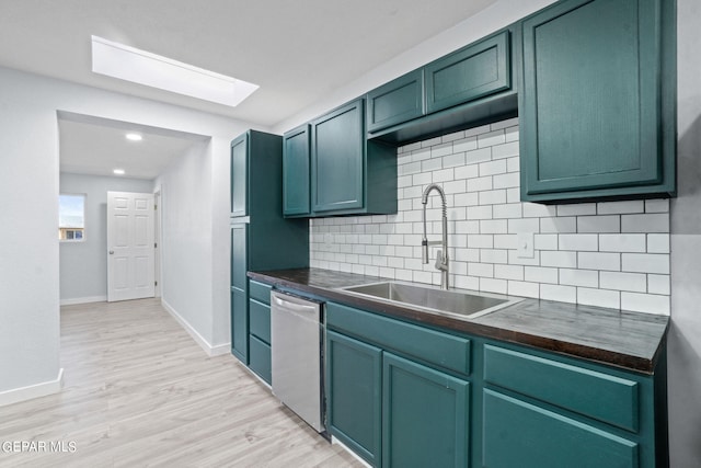 kitchen featuring a skylight, sink, light wood-type flooring, dishwasher, and tasteful backsplash