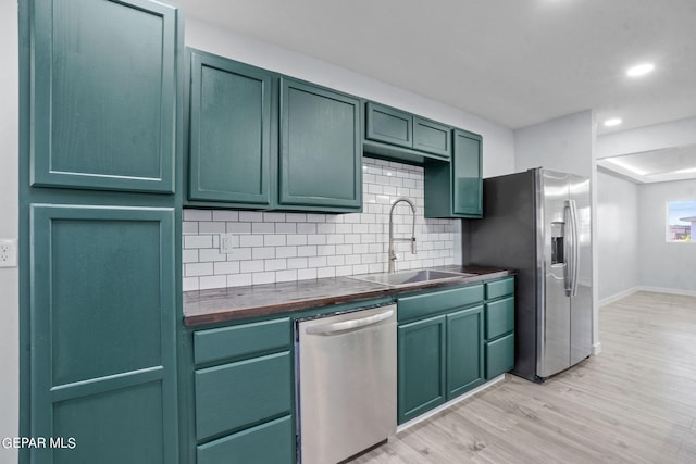 kitchen featuring green cabinetry, tasteful backsplash, stainless steel appliances, light hardwood / wood-style flooring, and sink