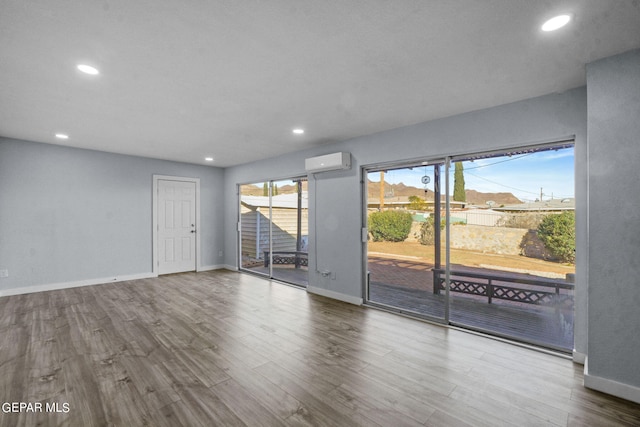 unfurnished room with light hardwood / wood-style flooring and an AC wall unit