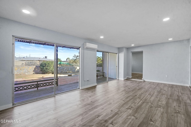 spare room with an AC wall unit and light hardwood / wood-style floors