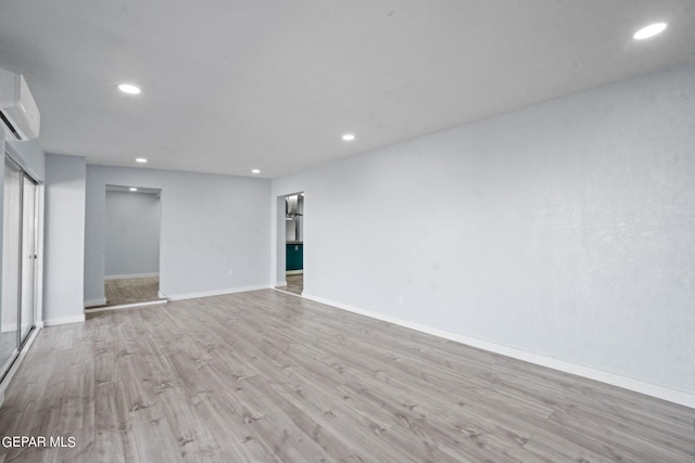 unfurnished room featuring a wall mounted AC and light wood-type flooring