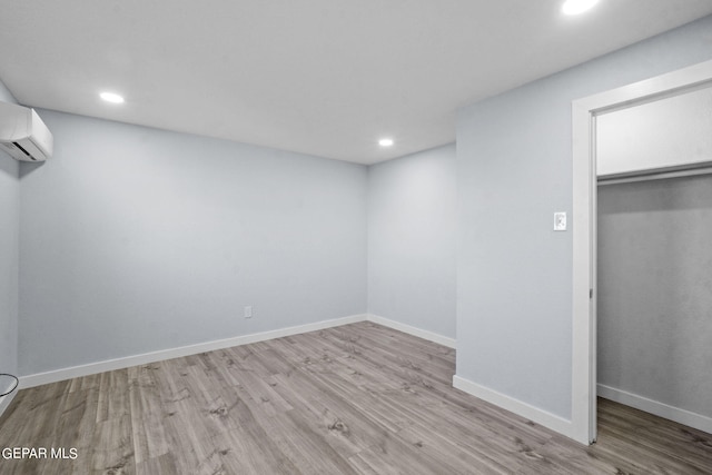 unfurnished bedroom featuring light hardwood / wood-style floors, a closet, and an AC wall unit