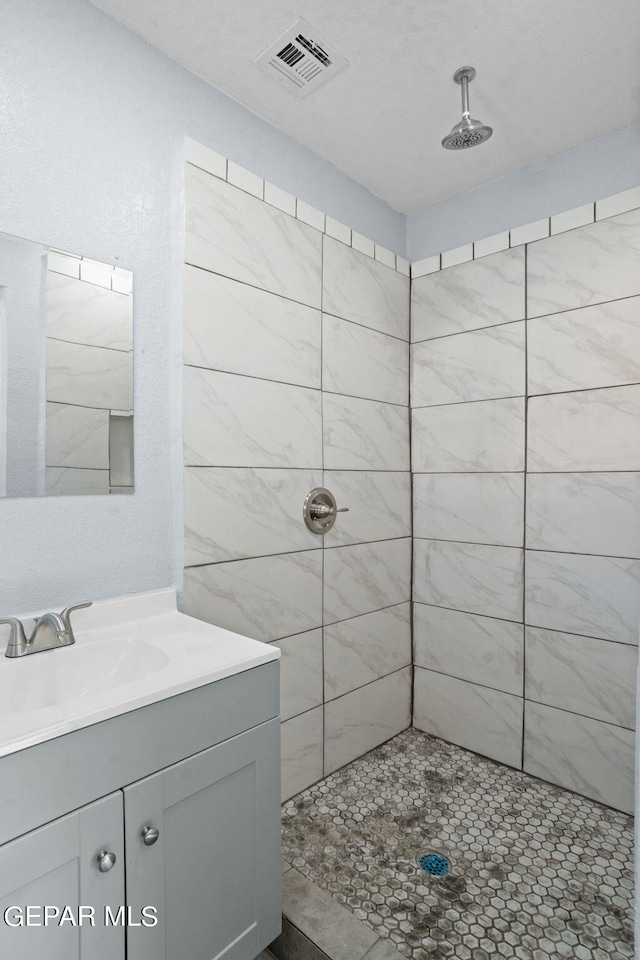 bathroom with large vanity and tiled shower