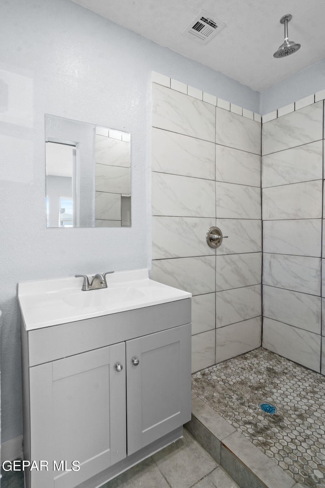 bathroom with tile floors, vanity, and tiled shower