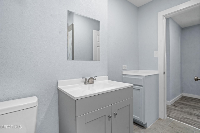 bathroom with toilet, vanity, and tile flooring