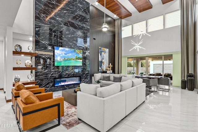 living room featuring a notable chandelier, a high end fireplace, light tile floors, and a towering ceiling