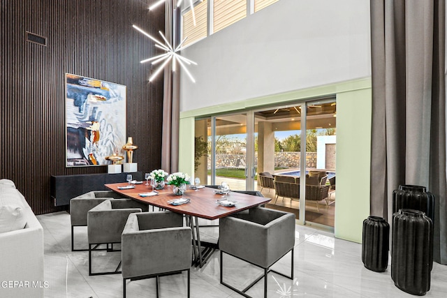 tiled dining area featuring a chandelier and a towering ceiling