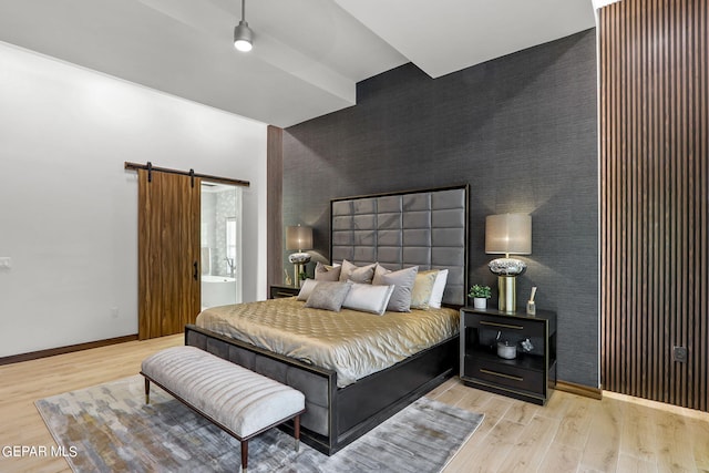 bedroom with a barn door and light wood-type flooring