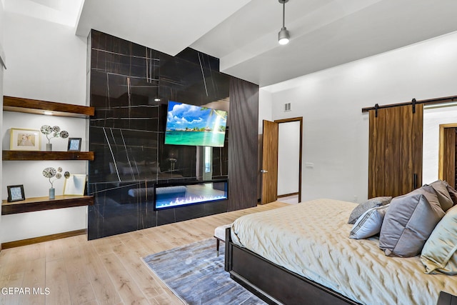 bedroom featuring a barn door, tile walls, and light hardwood / wood-style flooring