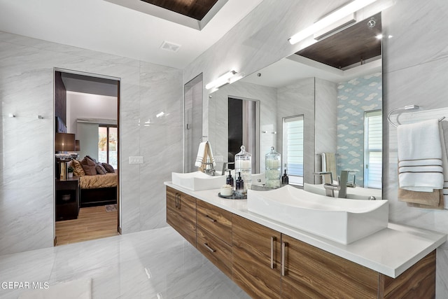 bathroom with tile walls, a tray ceiling, tile flooring, and oversized vanity