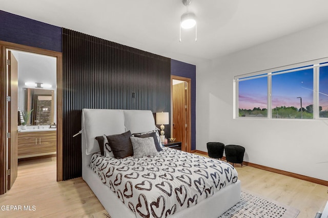 bedroom featuring ceiling fan, connected bathroom, and light hardwood / wood-style flooring