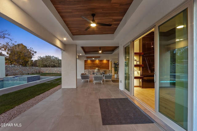 patio terrace at dusk with a fenced in pool and ceiling fan