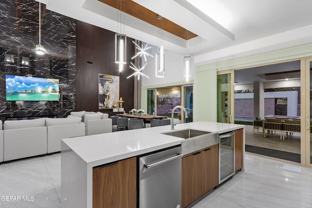 kitchen with wine cooler, stainless steel dishwasher, pendant lighting, a kitchen island with sink, and sink