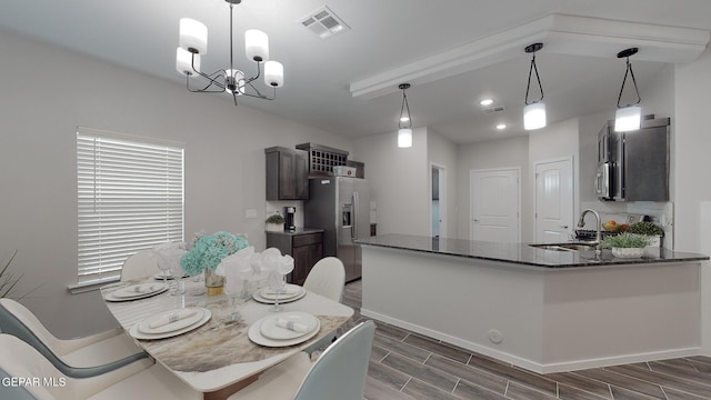 kitchen with a chandelier, pendant lighting, appliances with stainless steel finishes, dark brown cabinetry, and sink