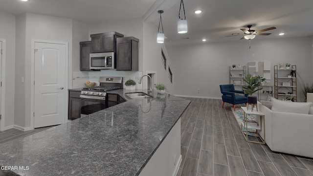 kitchen with ceiling fan, sink, light wood-type flooring, stainless steel appliances, and pendant lighting