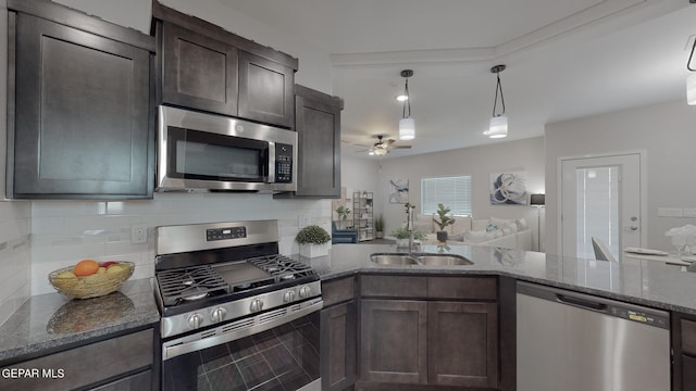 kitchen with stainless steel appliances, dark stone counters, hanging light fixtures, ceiling fan, and dark brown cabinetry