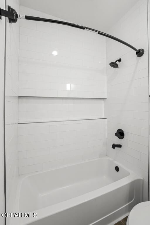 bathroom featuring toilet and tiled shower / bath combo