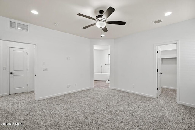 unfurnished bedroom featuring light colored carpet, a closet, ceiling fan, and a walk in closet