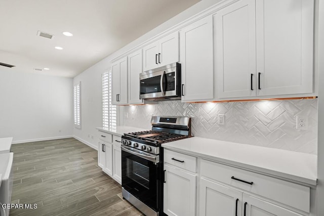 kitchen with white cabinets, stainless steel appliances, light wood-type flooring, and tasteful backsplash