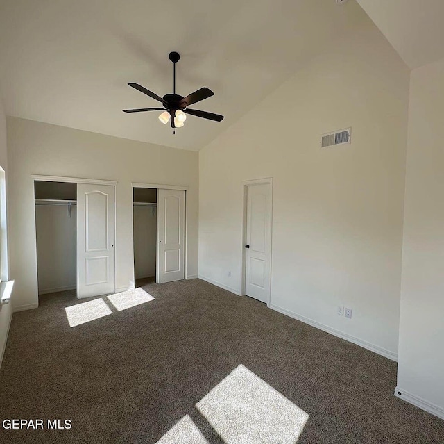 unfurnished bedroom with two closets, ceiling fan, and dark colored carpet