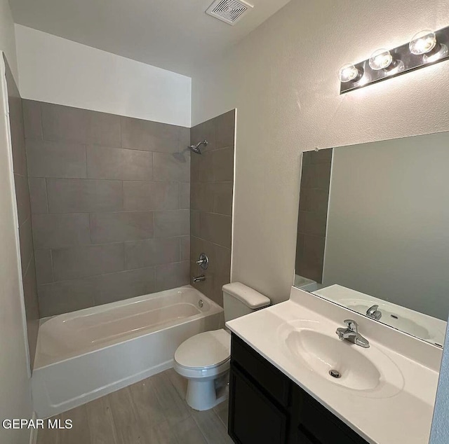 full bathroom with hardwood / wood-style flooring, vanity, toilet, and tiled shower / bath