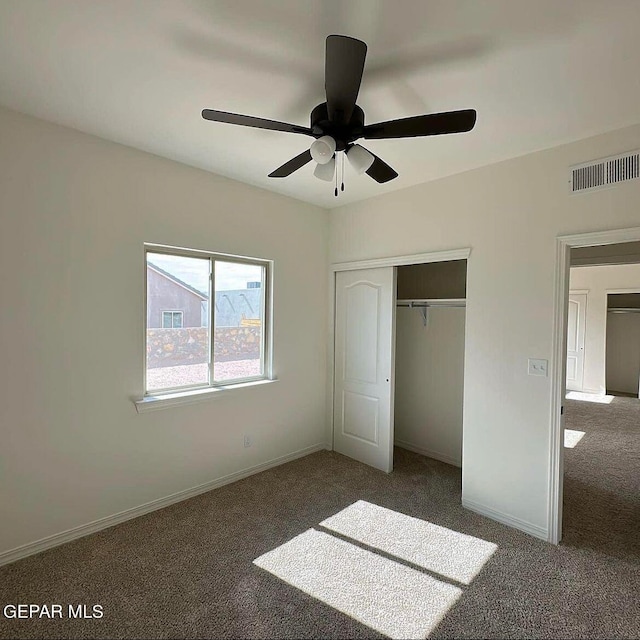 unfurnished bedroom with ceiling fan, a closet, and dark colored carpet