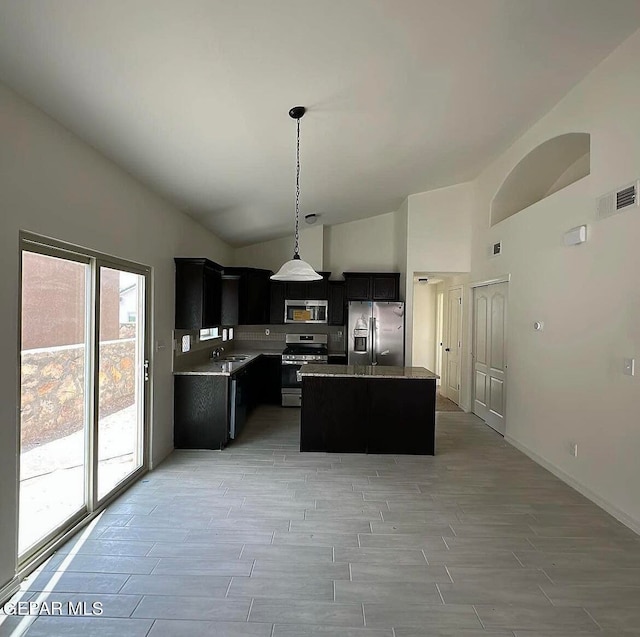 kitchen featuring stainless steel appliances, decorative light fixtures, a kitchen island, high vaulted ceiling, and sink