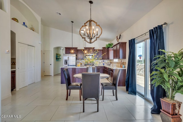 dining space featuring lofted ceiling, light tile flooring, a chandelier, and a wealth of natural light