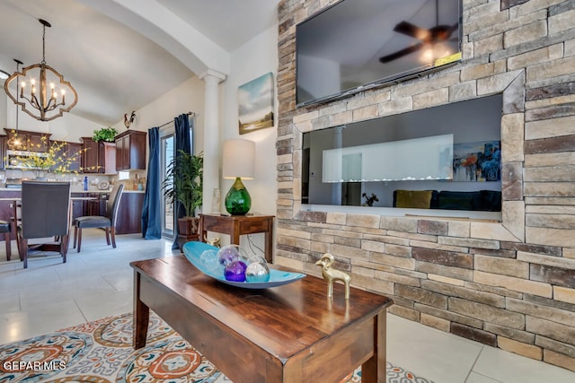 tiled living room featuring vaulted ceiling, decorative columns, and ceiling fan with notable chandelier