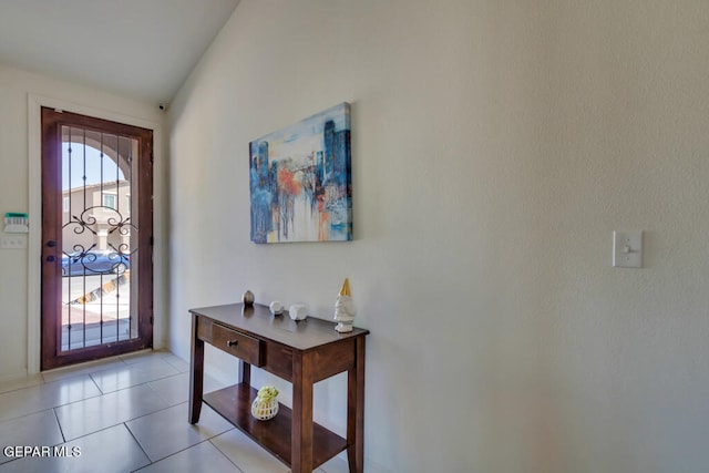 entrance foyer featuring vaulted ceiling and light tile floors