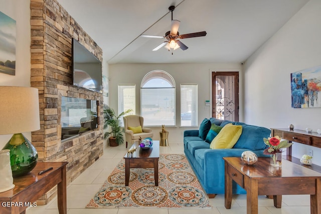 tiled living room with a stone fireplace and ceiling fan