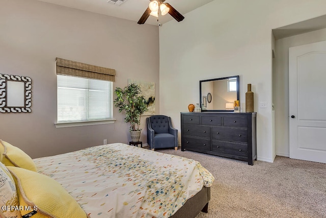 carpeted bedroom featuring ceiling fan and a towering ceiling