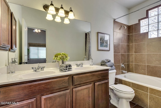 full bathroom with tiled shower / bath combo, tile floors, dual sinks, vanity with extensive cabinet space, and toilet