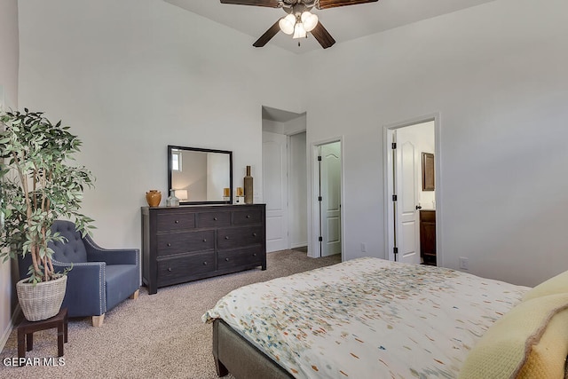 bedroom with ceiling fan, connected bathroom, light colored carpet, and a towering ceiling