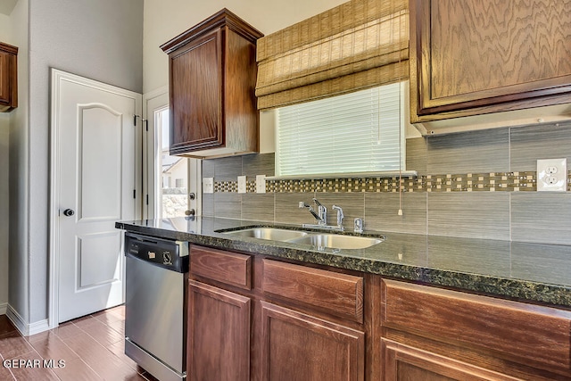 kitchen featuring dark stone counters, tasteful backsplash, wood-type flooring, dishwasher, and sink