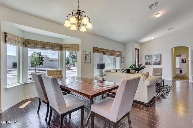 dining space featuring an inviting chandelier, vaulted ceiling, and dark hardwood / wood-style flooring