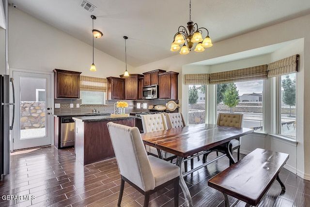 dining room with dark hardwood / wood-style floors, a notable chandelier, high vaulted ceiling, and a healthy amount of sunlight