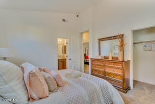 bedroom featuring light carpet, high vaulted ceiling, a closet, and ensuite bathroom