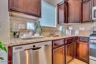 kitchen with backsplash, stainless steel appliances, and light stone counters