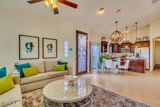 living room featuring ceiling fan with notable chandelier