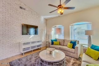 living room featuring brick wall, ceiling fan, hardwood / wood-style flooring, and lofted ceiling