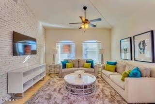 living room with brick wall, ceiling fan, and light wood-type flooring