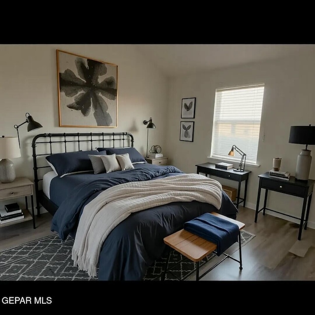 bedroom with baseboards, lofted ceiling, and wood finished floors