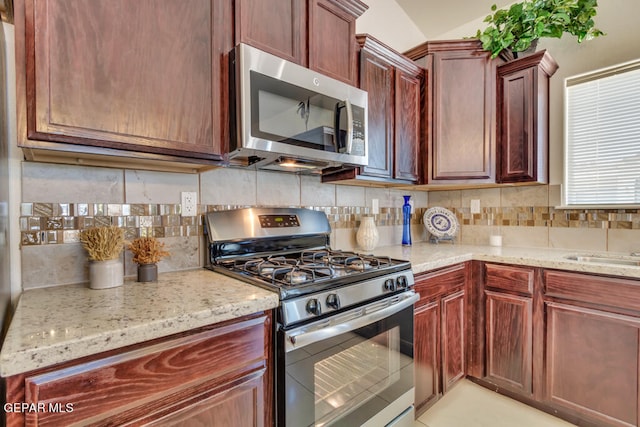 kitchen with appliances with stainless steel finishes, tasteful backsplash, and light stone counters