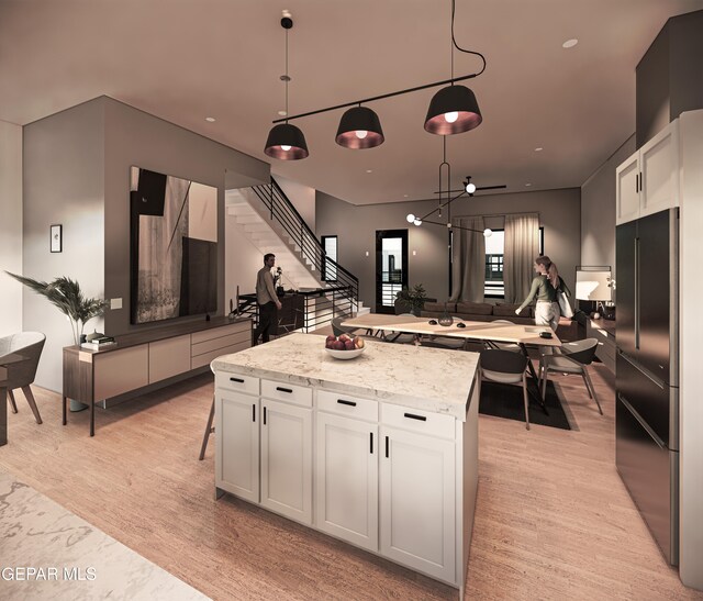 kitchen with white cabinets, light hardwood / wood-style flooring, hanging light fixtures, and light stone countertops