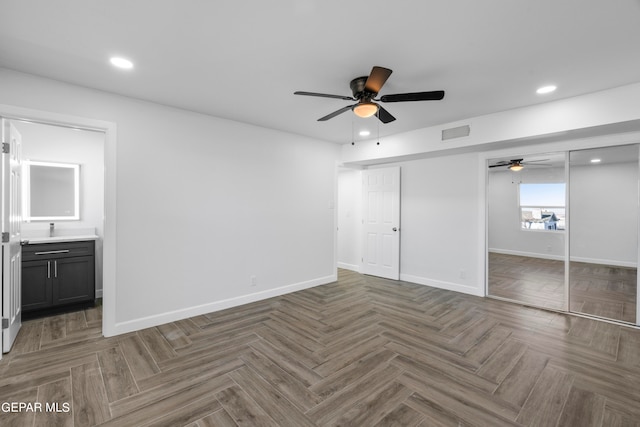 unfurnished bedroom with ensuite bath, dark parquet flooring, a closet, and ceiling fan