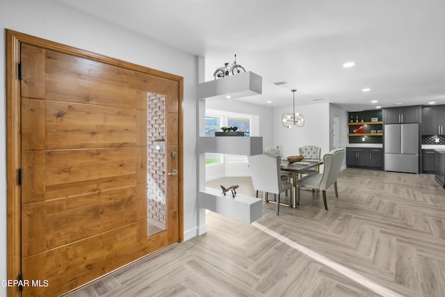 foyer featuring light parquet flooring and a notable chandelier