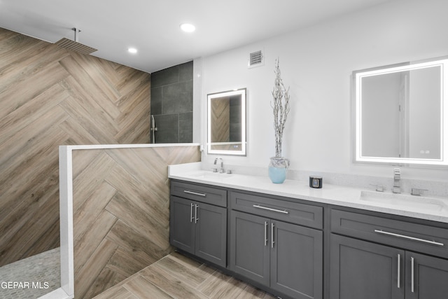 bathroom with parquet floors, double vanity, and a tile shower